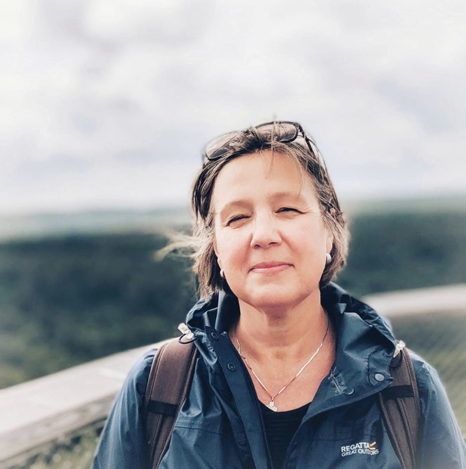 Frau mit Jacke steht vor bewölktem Himmel