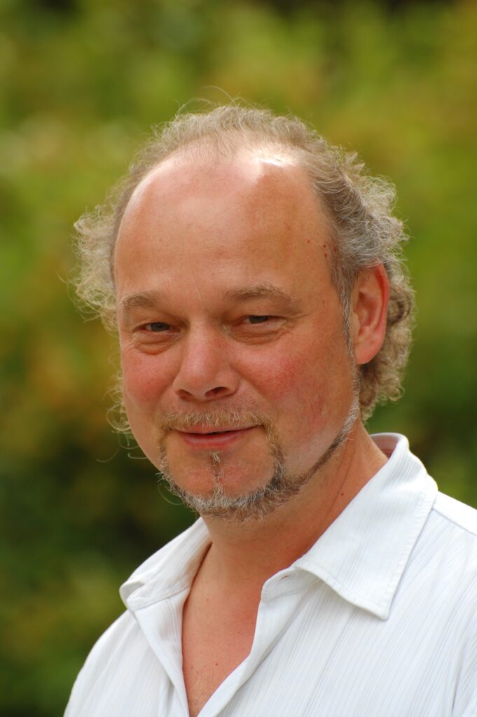 Mann mit Bart und weißem Hemd im Freien.