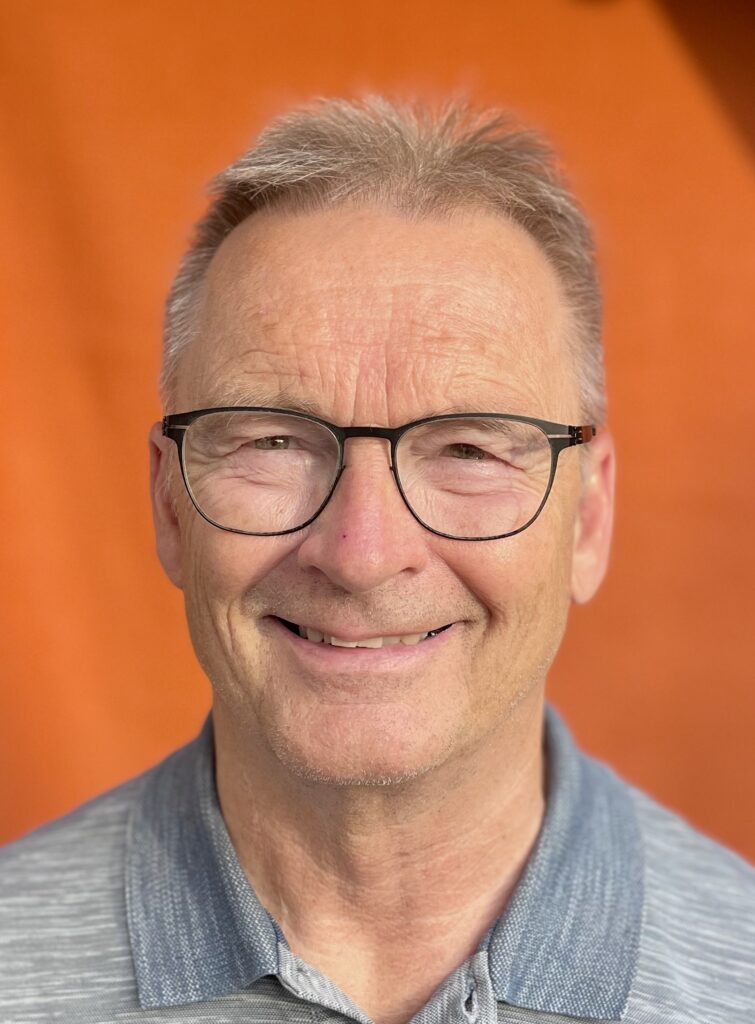 Älterer Mann mit Brille vor orangefarbenem Hintergrund