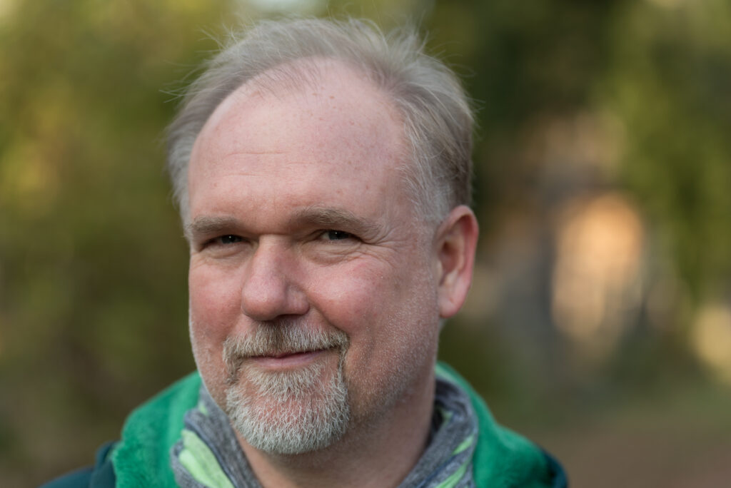 Mann mit grünem Hoodie im Freien lächelnd