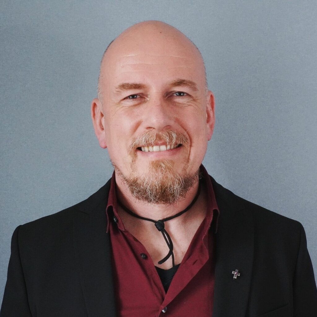 Mann mit Glatze und Bart in Anzugjacke