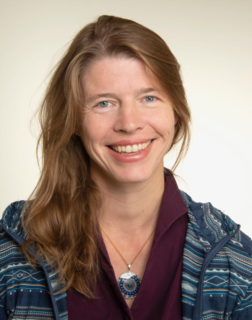 Frau lächelt in einem blauen gestreiften Pullover.