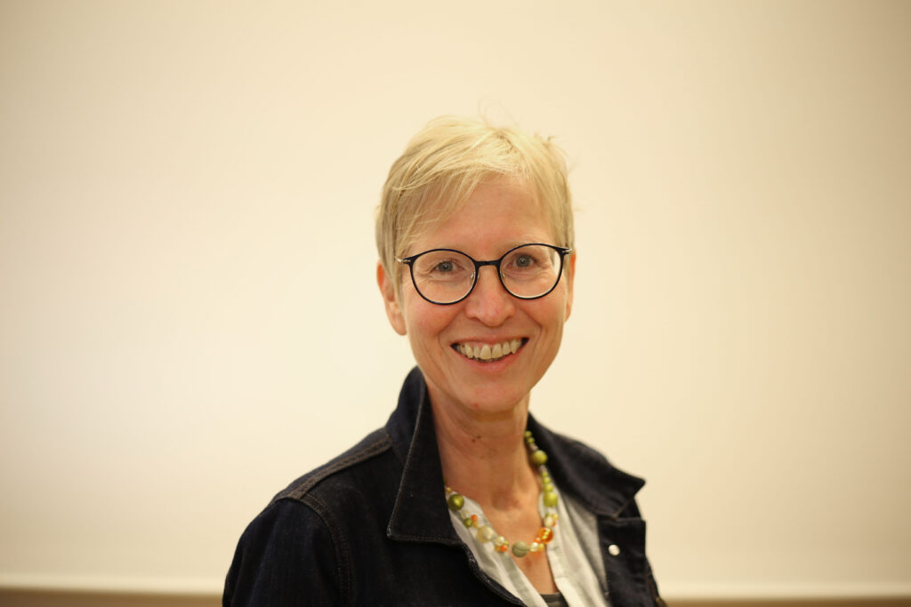 Dame mit Brille und Kurzhaarfrisur vor hellem Hintergrund