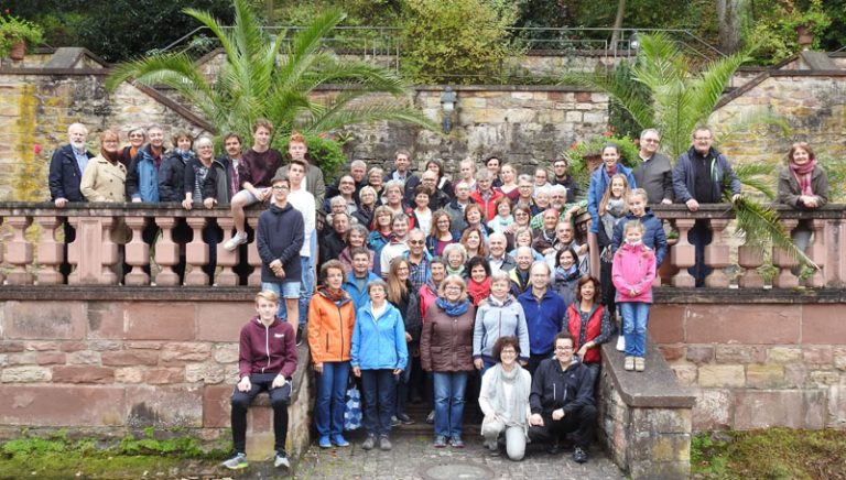 Gruppe von Menschen posiert vor historischer Mauer.