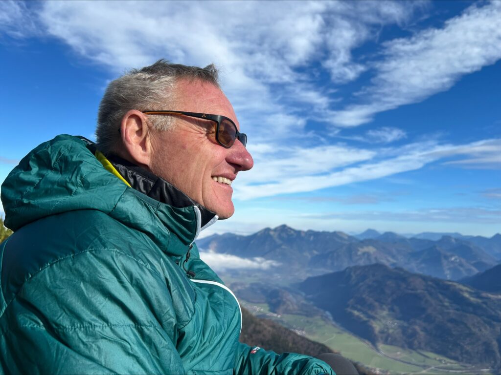 Älterer Mann in den Bergen bei Sonnenschein