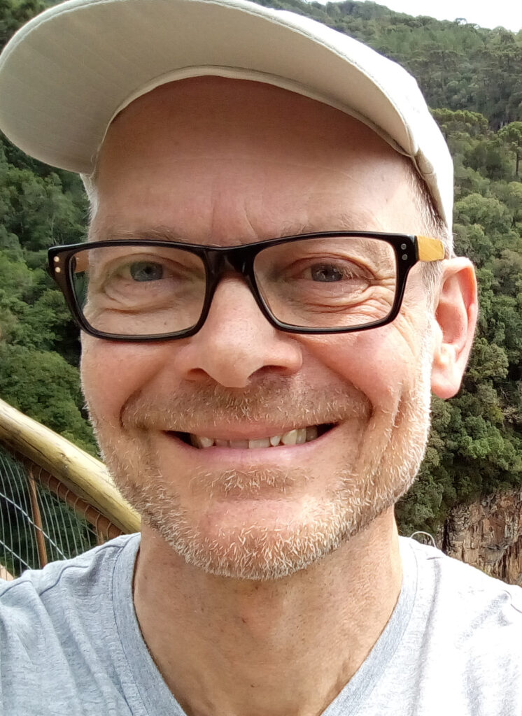 Mann mit Brille und Mütze lächelnd im Freien