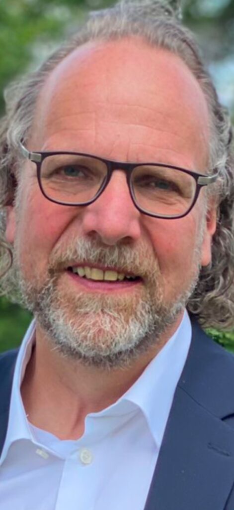 Mann mit Brille und Bart im Anzug draußen