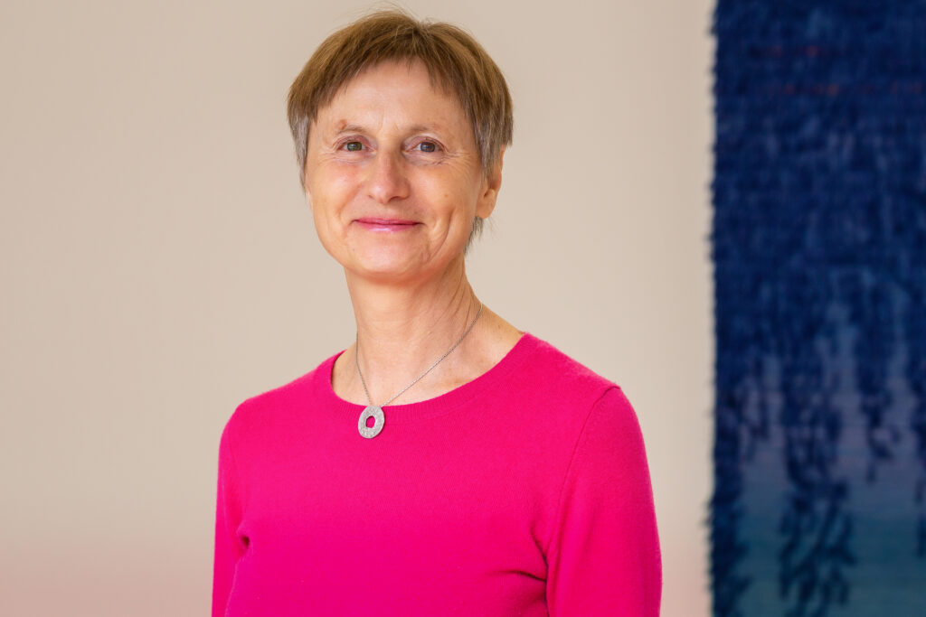 Dame in rosa Bluse lächelt vor Wandkunst