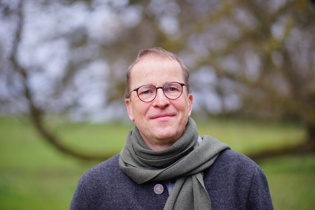 Mann mit Brille und Schal im Freien fotografiert
