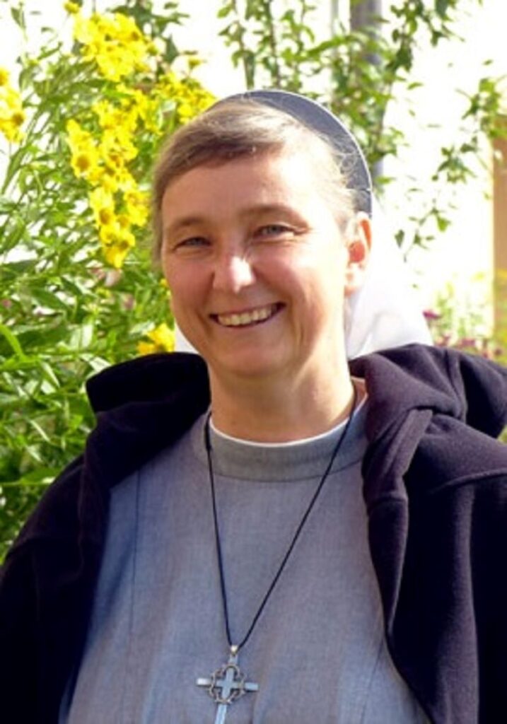 Lächelnde Nonne im Garten mit gelben Blumen