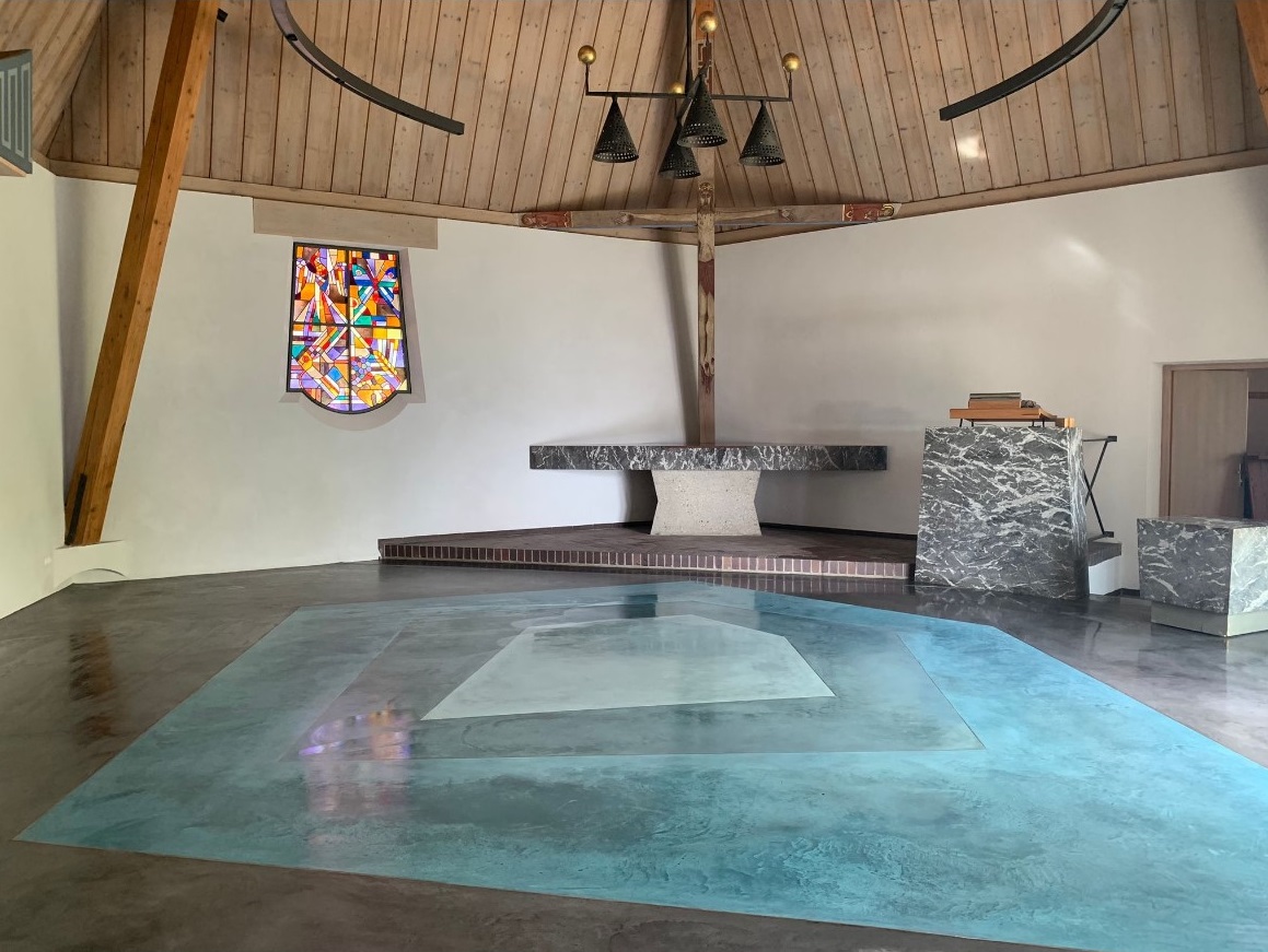 Moderner Kircheninnenraum mit Altar und buntem Glasfenster