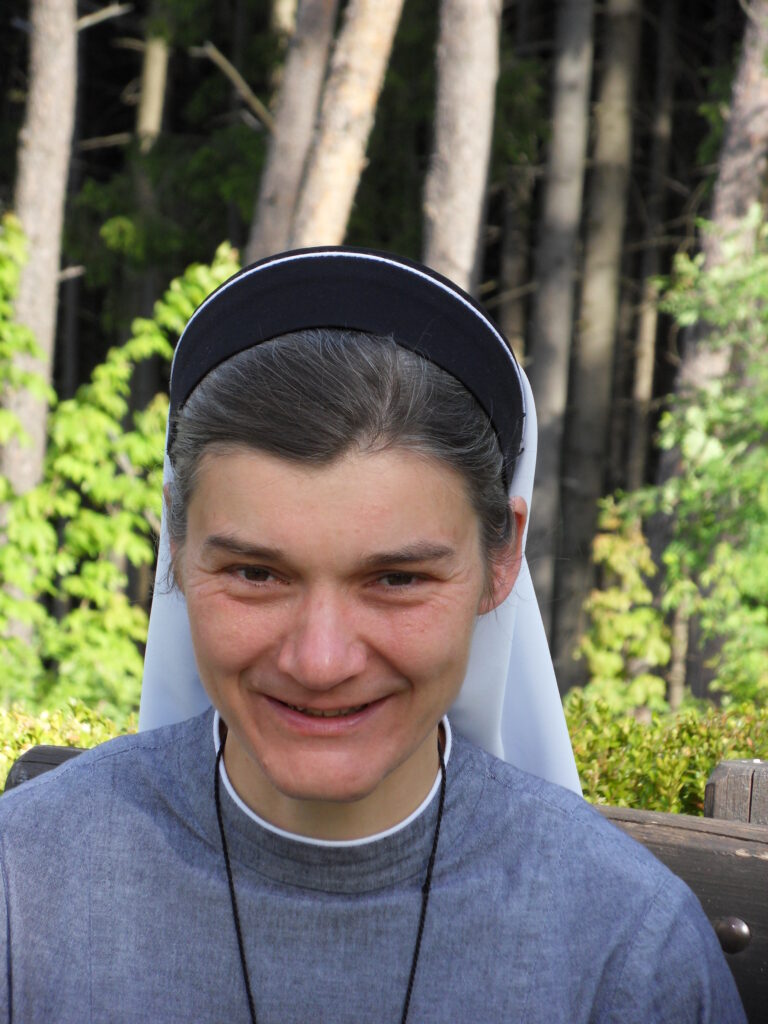 Frau in Nonnenkleidung lächelt im sonnigen Wald